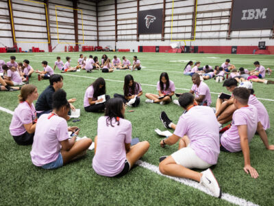 Groups of First Tee participants sitting on the Atlanta Falcons field