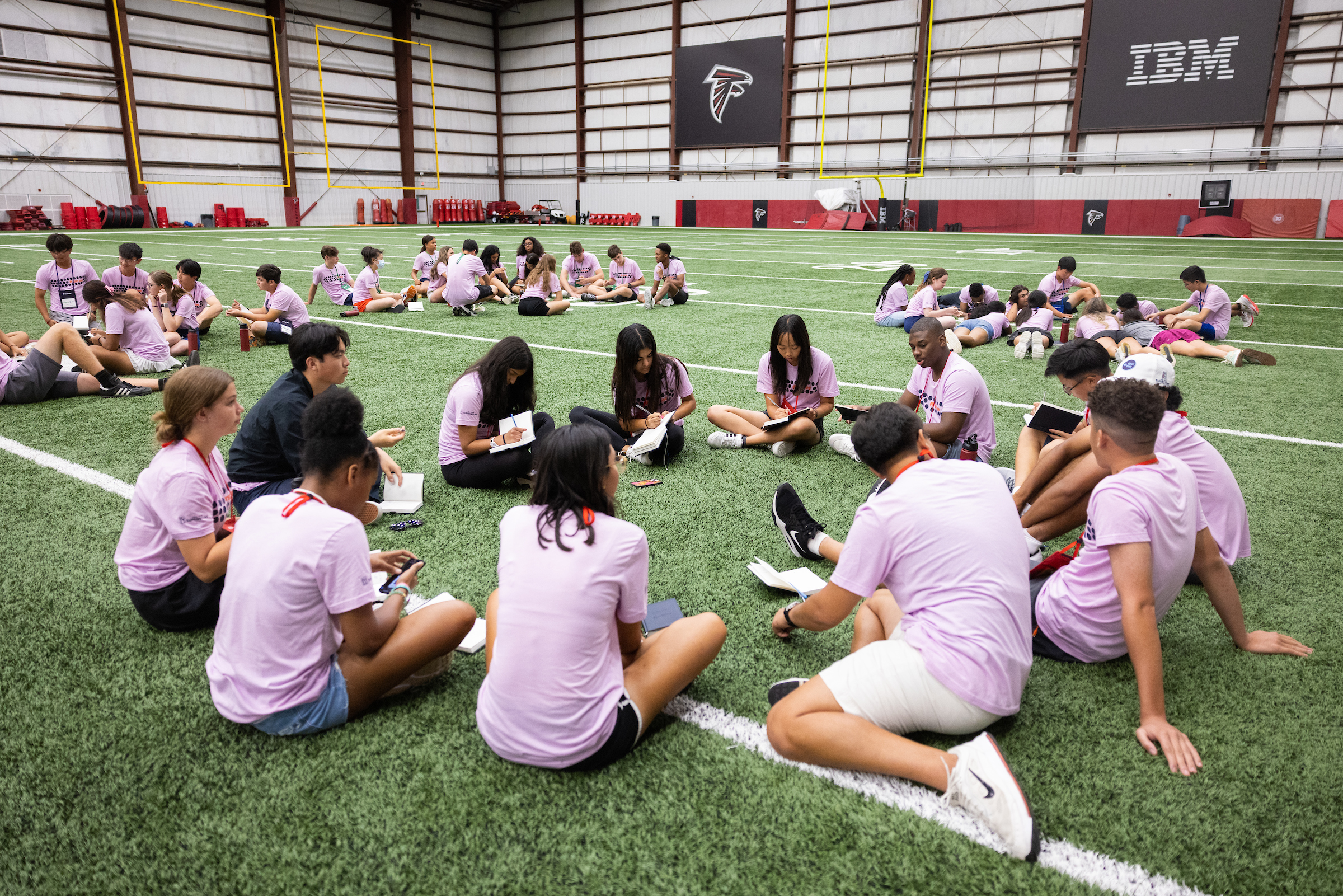 Groups of First Tee participants sitting on the Atlanta Falcons field