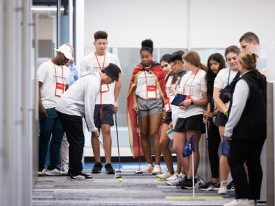 Group of First Tee participants putting in an office.