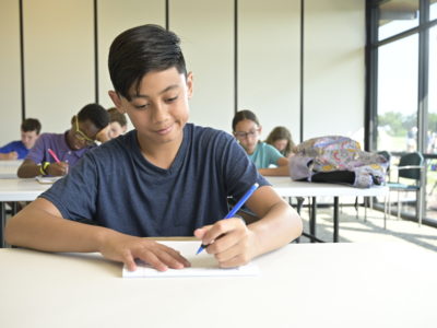 Boy taking notes in a classroom.