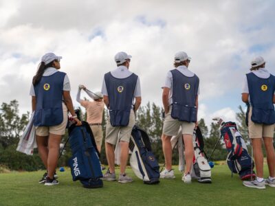 Group of participants caddying and posing on a golf course.