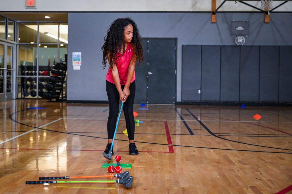 Participant doing a golf activity in a gym.