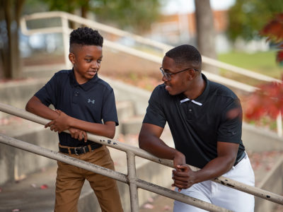 First Tee mentor speaks with young boy.