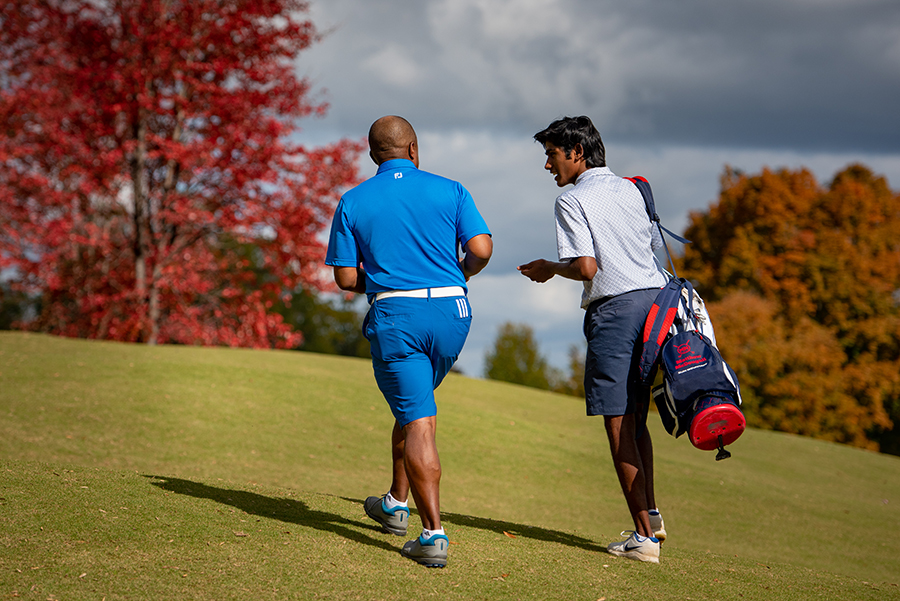First Tee coach and participant talk on a golf course.