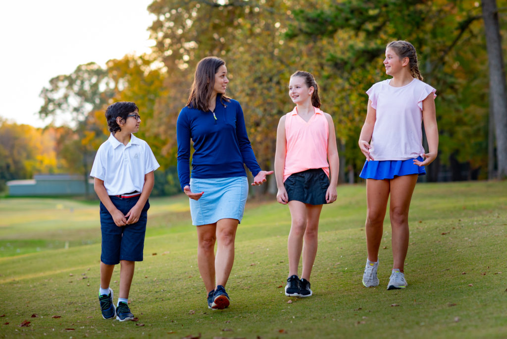 First Tee participants and coach walking on a golf course.